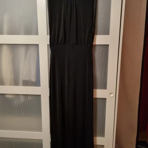 Byxdress/jumpsuit från Bik Bok - Svart jumpsuit/byxdress från Bik Bok med djup v-ringning i ryggen och ärmlös design. Glittrig, vida ben. Använd 1 gång.