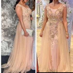 Champagnefärgad långklänning med spetsdetaljer - Elegant champagnefärgad långklänning med vackra spetsdetaljer och broderier. Klänningen har en ärmlös design och en lätt transparent överkjol som ger en drömlik känsla. Perfekt för speciella tillfällen.