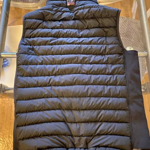 Svart dunväst med dragkedja - Säljer en stilren svart dunväst från Parajumpers. Västen har en praktisk dragkedja framtill och två fickor med dragkedjor. Kvitto ska finnas nån stans här hemma 