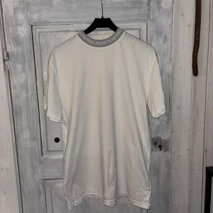 Acne Studios tröja - Säljer en stilren vit t-shirt från Acne Studios. Enda problemet är att det är någon fläck på sidan och lite på framsidan (inte jätte synligt). Går säkert att ta bort om man har nått bra knep. 