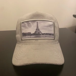 Grå velvet keps med Eiffeltorn motiv  - Snygg grå keps från Rovior med ett motiv av Eiffeltornet på framsidan. Kepsen har ett nätmaterial på baksidan för bättre ventilation och en justerbar rem för perfekt passform. 