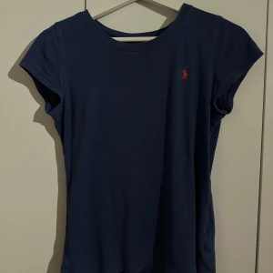 Mörkblå t-shirt från Ralph Lauren - Säljer en stilren mörkblå t-shirt från Ralph Lauren med korta ärmar och en liten röd logga. Den har inga defekter och är otroligt mjuk och skön. Den passar någon som är xs-s
