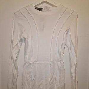 Vit jumpsuit med dragkedja - Snygg vit unitard/jumpsuit med lång ärm och dragkedja baktill. Den har en figurnära passform och stilrena sömmar som ger en modern look. Perfekt för en stilren och enkel outfit. Garderobsrensning så kika gärna på övriga auktioner.