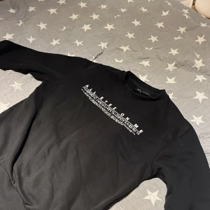 Svart sweatshirt med Tupac-tryck - Snygg svart sweatshirt med tryck av Tupac och texten 'All Eyes On Me'. Tröjan har långa ärmar och en bekväm passform. Perfekt för dig som vill ha en stilren och cool look. I st xs men passar s bäst 