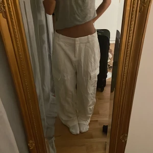 Vita cargobyxor - 💕Säljer ett par vita cargobyxor med flera fickor och en loose passform. Byxorna har en låg midja och är perfekta för en avslappnad stil. De är tillverkade i ett bekvämt material som passar bra för både vår och sommar. Passar bra med en somrig topp💕