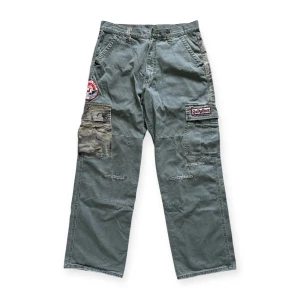 Vintage Quiksilver cargobyxor med patchar - Snygga vintagebyxor från märket Quicksikver. Väldigt rare. Knappen över gylfen har tyvärr gått av men en ny knapp kan enkelt sättas dit! I fint skick annars. Mått: längd 106 cm, inseam 79 cm, midja 41 cm, lår 33 cm, knä 27 cm, benöppning 25 cm.