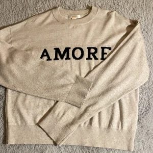 Beige tröja med text från Gina Tricot - Säljer en beige tröja från Gina Tricot med texten 'AMORE' i svart på framsidan. Storlek 158/164! Använt fåtal gånger och är i bra skick! Tveka inte om frågor!🙂❤️
