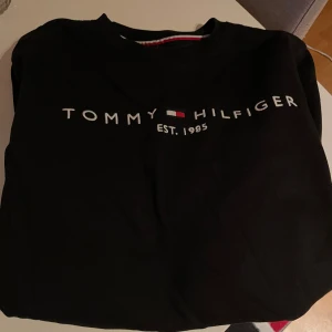 Svart tröja från Tommy Hilfiger storlek S - Säljer en stilren svart sweatshirt från Tommy Hilfiger med logotyp och text 'EST. 1985' på framsidan. Använd 1-2 gånger, så i nyskick. Ordinarie pris 1200 :-Hämtas i Sollentuna Stockholm eller skickas mot fraktkostnad.