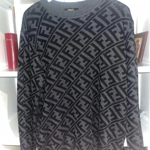  Fendi Tröja - Snygg svart och grå tröja från Fendi med ett iögonfallande mönster av märkets logotyp. Tröjan har långa ärmar och en rund halsringning, perfekt för en stilren look.Helt ny också 