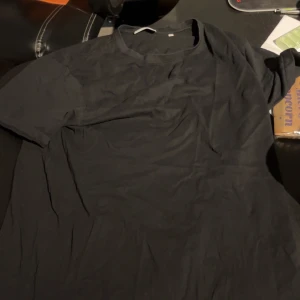 Svart t-shirt från Lindbergh - Säljer en klassisk svart t-shirt från Lindbergh i storlek L. Perfekt basplagg med rund hals och korta ärmar. Enkel och stilren design som passar till det mesta.