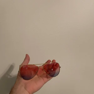 Aviator solglasögon med guld bågar - Snygga aviator solglasögon med guld färgade bågar och spegelglas i röd nyans. Perfekta för en cool look i solen.