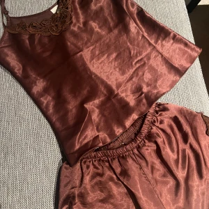 Vinrött satinlinne med spetsdetaljer - Ett fint vinrött pyjamas sett i shorts och linne med spets detaljer, passar s och m
