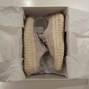 Beige sneakers från Y-3 - Snygga beige sneakers från Y-3 med en chunky sula och diskret snörning. Perfekta för en stilren look med en modern touch. Skorna har en unik design med tydliga linjer. Nypris ca 2000kr