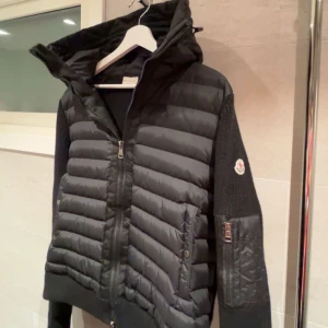 monclear cardigan  - Säljer en snygg svart cardigan från monclear med stickade armar. Perfekt för både höst och vinter håller dig varm o stilren. Passar både till vardags och lite finare tillfällen.  bra skick. Den är köpt på plick för ett årsen för runt  5000 pris kan diskuteras vid snabb affär