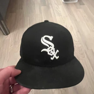 Svart SOX keps - TVÄTTAR INNAN JA SKICKAR! Snygg svart keps från New Era med vit broderad logga på framsidan. Perfekt för sportiga tillfällen eller som en stilren accessoar. Kepsen har en klassisk passform och är en del av 59FIFTY-serien.