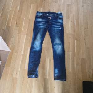Snygga blå jeans från Dsquared2 med en cool tvättad look och slitningar. De har en knappgylf och klassisk femficksdesign. Perfekta för en trendig stil.