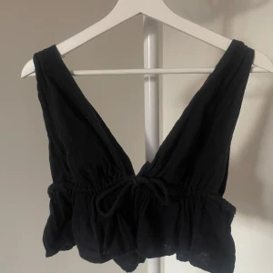 Svart ärmlös topp med knyt - Fin fest/sommartopp med djup v-ringning både fram och bak. Har även sytt upp vid axlarna, men det är bara att ta bort om man vill då tyget är kvar. Köpt på bikbok.