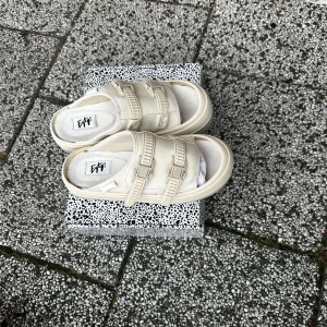 Beige sandaler från Eytys - Snygga beige sandaler från Eytys med dubbla remmar och spännen. Perfekta för en avslappnad stil. Sandalerna har en robust sula och är tillverkade i canvasmaterial.