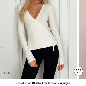 Vit omlottopp - Snygg vit omlottopp med långa ärmar och knytband i midjan. Perfekt för en stilren look. Använts 1 gång. 