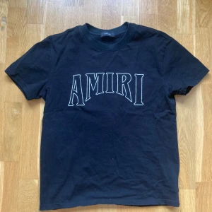 Svart t-shirt från Amiri Medium - Snygg svart t-shirt från Amiri med stort tryck av solmotiv på baksidan och Amiri-logga på framsidan. Perfekt för en stilren och cool look.