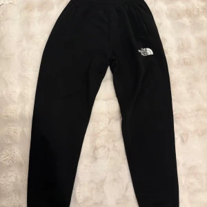 The North Face tracksuit - Säljer en svart hoodie från The North Face, Summit Series. Den har en klassisk design med huva och dragsko samt en stor logga på bröstet. Perfekt för kyliga dagar och outdoor-äventyr.