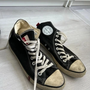 Svarta sneakers från Levi's - Snygga svarta sneakers från Levi's med vita snören och en rund logga på sidan. Skorna har en klassisk design med gummisula och vita detaljer på tå och sula. Perfekta för en avslappnad stil.