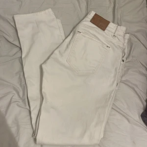 Vita jeans från Morris - Snygga vita jeans från Morris med klassisk design. De har en midwaist passform och är tillverkade i bomull. Perfekta för en stilren look med knappar och dragkedja framtill. Storlek 32/32