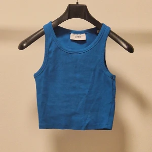 Blå tanktopp - Snygg blå tanktopp från JJXX. Perfekt för varma dagar med sin ärmlösa design och bekväma passform. Enkel och stilren, passar till många olika outfits.