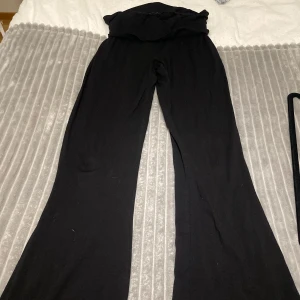 Svarta byxor med vida ben - Säljer ett par svarta byxor med vida ben och hög midja. Perfekta för en avslappnad stil. Byxorna är tillverkade i ett mjukt material som ger en bekväm passform. Dock finns ett hål vid vikningstyget som inte syns vid användning och går att sy ifall man vill