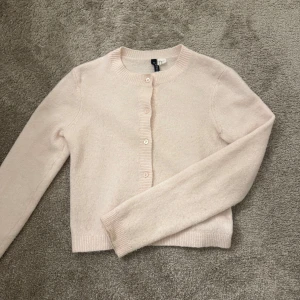 Ljusrosa kofta från H&M - Säljer en söt ljusrosa kofta från H&M. Den är stickad och har långa ärmar med knappar framtill. 