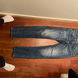 Blå jeans från Replay - Säljer ett par snygga blå jeans från Replay, modell Grover. De har en klassisk femficksdesign och slitna detaljer för en cool look. Perfekta för en avslappnad stil.