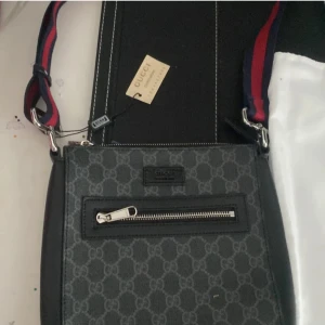 Svart axelväska från Gucci - Snygg svart axelväska från Gucci med det ikoniska mönstret. Och väskan är väldigt stilig och jag har aldrig använt den så det är perfekt skick