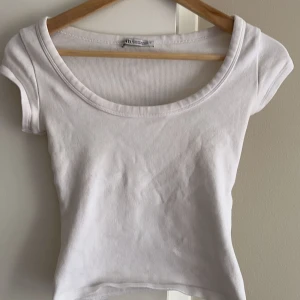 Vit ribbad kortärmad topp - Säljer en stilren vit ribbad topp från ZARA.  Den har en rund halsringning och korta ärmar, perfekt för en avslappnad look. Passar bra till jeans eller kjol. (EGNA BILDER PRIVAT) 