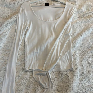 Vit långärmad topp - Säljer en stilren vit långärmad topp med rund halsringning från Gina tricot. Har slits på armen, och är väldig stilren 