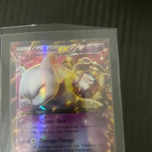 Mewtwo EX Pokémonkort - Säljer ett Mewtwo EX Pokémonkort med holografisk design. Kortet har en kraftfull illustration av Mewtwo och är en del av en samlarkollektion. Perfekt för Pokémon-entusiaster och samlare!