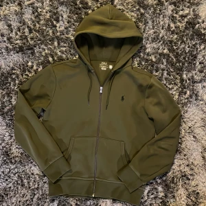 Ralph Lauren hoodie - En riktigt fet och helt oanvänd hoodie från RL. Tröjan är naturligtvis autentisk vilket går att känneteckna genom att scanna QR-koden som finns vid nacken. Köpt på Zalando för 2295 sek! Priset är som vanligt inte hugget i sten och kan tänkas gå ner i pris vid en snabb affär! 