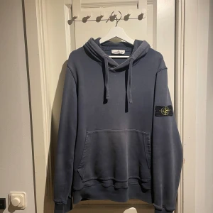 Stone Island hoodie - Säljer en skön hoodie från stone island. Färgen är blågrå och den är i storlek L. Hoodien har en liten distressed touch då den är aningen blekt i på vissa ställen men det är nånting jag tycker gör den snyggare (i övrigt i mycket bra skick), behöver dock rensa garderoben så därför är den här. Nypris är 2499 och prislappen finns kvar