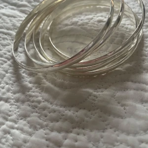 Set med sex silverfärgade armband - Snygga och stilrena silverfärgade armband i ett set om sex stycken. Perfekta för att bära tillsammans eller var för sig för en minimalistisk look. Passar till alla tillfällen och ger en cool touch till din outfit.