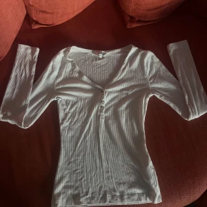 Vit ribbad långärmad topp från Lee - Säljer en stilren vit ribbad topp från Lee med lång ärm och v-ringning. Toppen har knappar framtill och är perfekt för en avslappnad look. Passar bra till jeans eller kjol. Perfekt för alla säsonger!🤍