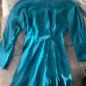 Turkos klänning - Snygg turkos klänning med långärmad design och elastisk midja för en bekväm passform. Perfekt för att lysa upp garderoben med sin livfulla färg.