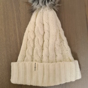 Vit stickad mössa från Race Marine - Mysig vit stickad mössa från Race Marine. Pälsen är fejk! Mössan har lite tecken på användning om man tittar nära men inget som syns annars.