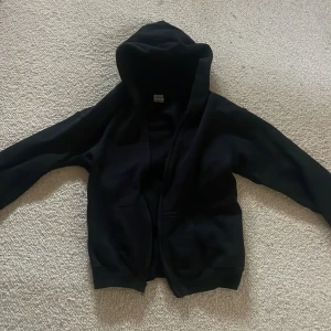 Svart hoodie med tryck - Säljer en svart hoodie med texten 'STREET FEET' i vitt på ryggen. Den har en bekväm passform med långa ärmar och en praktisk huva. Perfekt för en avslappnad stil.