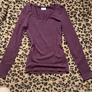 Vinröd långärmad topp - Säljer en stilren vinröd långärmad topp med rund halsringning. Perfekt för lager-på-lager eller som den är. Passar till både jeans och kjol. Enkelt och snyggt val för garderoben!