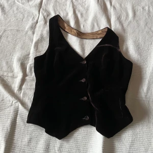 Brun sammetshalternecktopp - Fin brun halterneckväst  från märket ”hennes”. Toppen är i brunt sammetstyg med ett guldigt foder. Passar både att ha som en topp utan någonting under eller som en topp över tex en skjorta eller tröja🌟