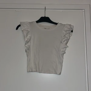 Vit ribbad topp från Zara - Vit ribbad topp med volangärmar från Zara. Den har några små fläckar. 🩷