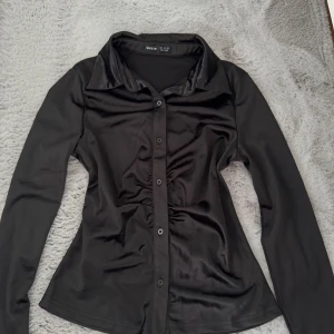 Svart långärmad skjorta från Shein - Snygg svart skjorta helt ny aldrig använd, med långa ärmar och knappar framtill. Skjortan har en elegant krage och en figurnära passform som ger en stilren look. Perfekt för att höja din outfit till nästa nivå!