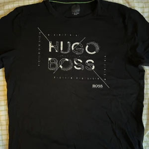 Svart t-shirt från Hugo Boss - Snygg svart t-shirt från Hugo Boss med ett stilrent tryck i vitt på framsidan. Perfekt för en casual look.