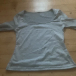 Grå långärmad topp - Säljer en stilren grå långärmad topp med rund halsringning. Perfekt för en enkel och bekväm look. Passar bra till både jeans och kjol.