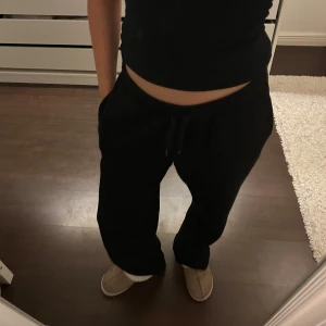 Svarta mjukisbyxor low waist Gina tricot  - Säljer ett par svarta mjukisbyxor med snörning i midjan. Perfekta för en avslappnad stil och bekväma att bära hemma eller på språng.