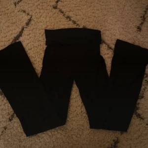Svarta yoga byxor  - Snygga svarta yogabyxor från Gina Tricot i storlek 146/152. Perfekta för en bekväm och stilren look. De har lågmidja med en nerfällbar kant och har en tight passform med utsvänga ben nertill❤️